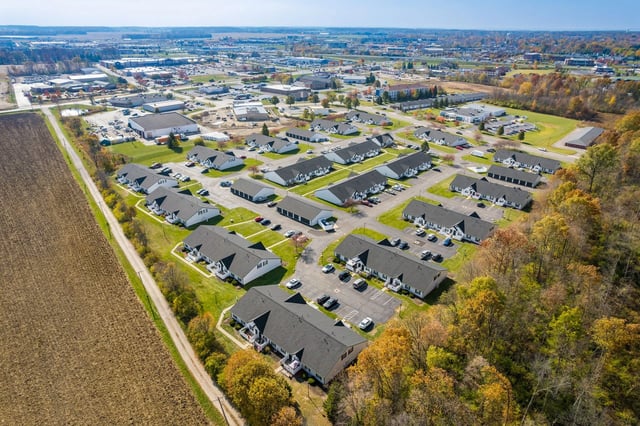 Aerial view of a multifamily property with multiple buildings, parking lots, and surrounding landscaping.