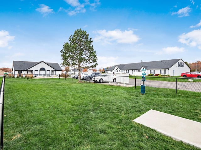 Green lawn with a dog waste station in front of apartment buildings.
