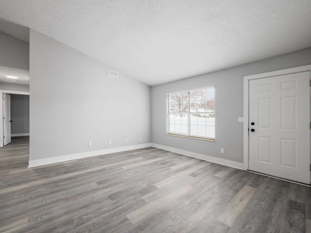Living room with white front door and window overlooking trees
