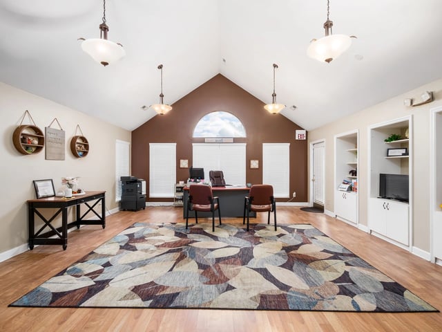 Modern leasing office with a large rug, reception desk, and amenities.