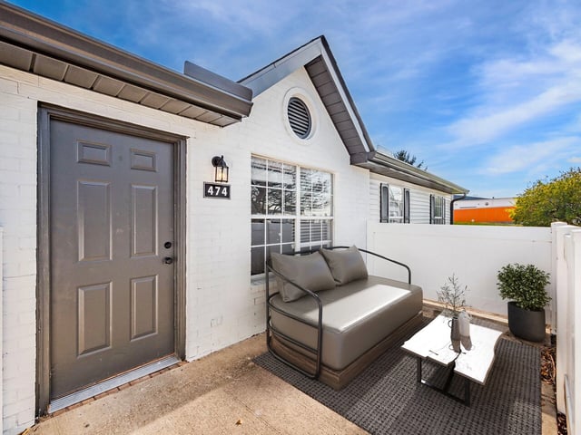 Exterior view of apartment 474 with a grey door and patio seating.