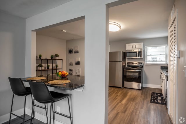 Kitchen and dining area with bar seating and stainless steel appliances.