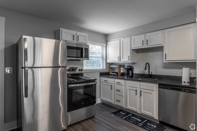 Stainless steel refrigerator, oven, microwave, dishwasher, and white cabinets in a modern kitchen.
