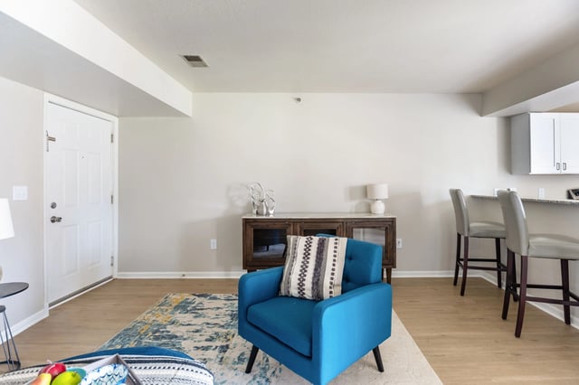 Living room area with a blue armchair, rug, and a console table.