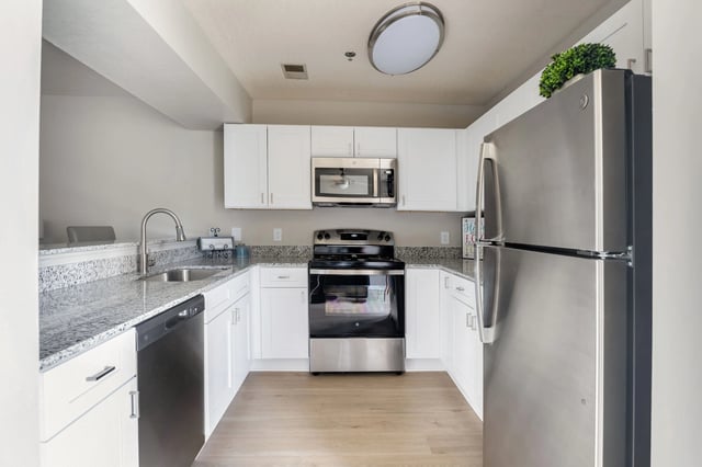 Modern U-shaped kitchen with stainless steel appliances and granite countertops.