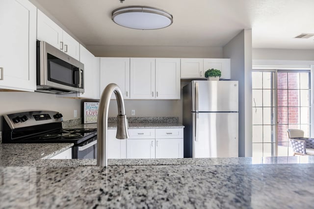 Modern kitchen with stainless steel appliances, granite countertops, and white cabinetry.
