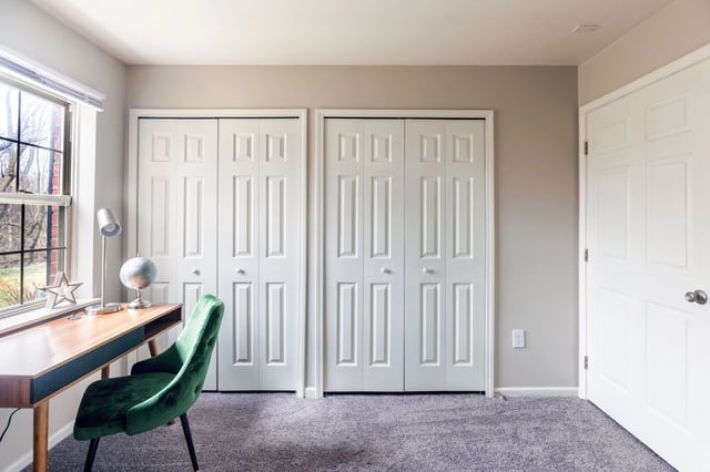 Closet doors and a desk with a chair in a bedroom.