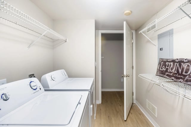 Laundry room with stacked washer and dryer, shelving, and a decorative sign.