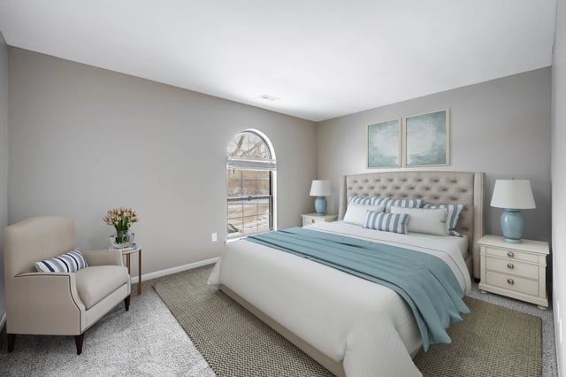 Bedroom with a king-size bed, armchair, and arched window.