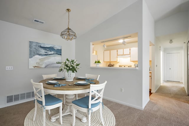 Dining area with round table and chairs, view into kitchen.