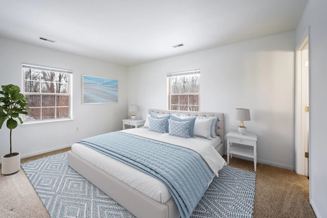 Bedroom with a queen-size bed, bedside tables, and windows.