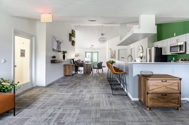 Community common area with seating, a bar with stools, and a kitchen.