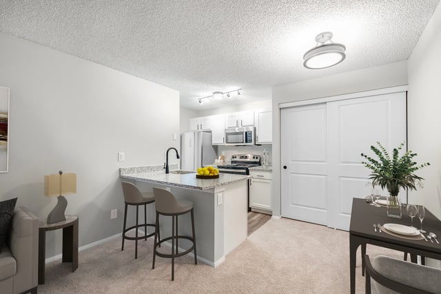Modern kitchen with granite countertops, stainless steel appliances, and breakfast bar with stools.
