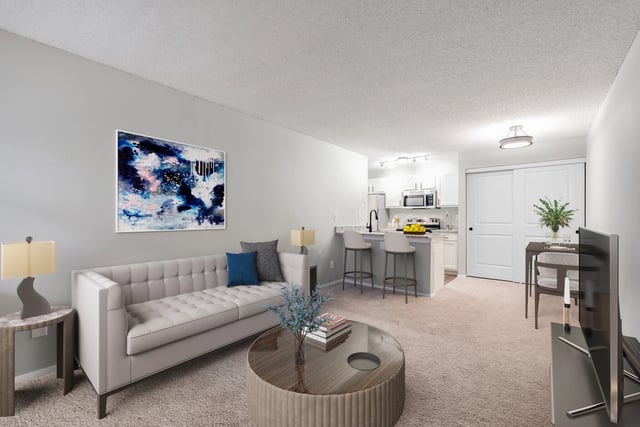 Living room with a sofa, coffee table, and kitchen with bar seating.