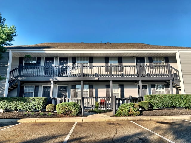 Apartment building exterior with parking lot in front.