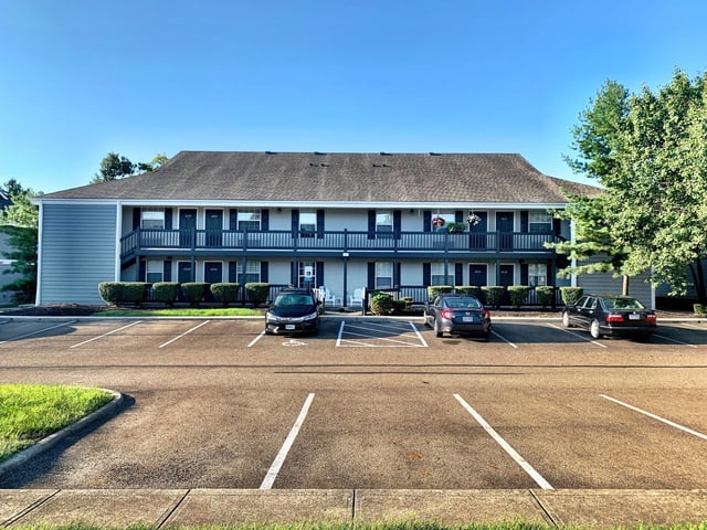 Apartment building exterior with parking lot and cars.