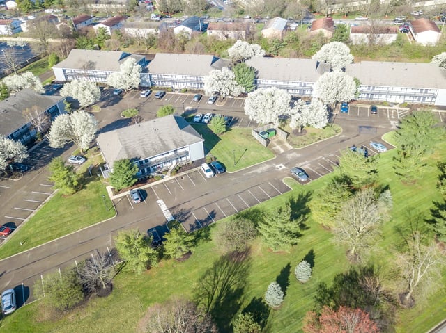 Aerial view of apartment buildings and parking lots with blooming trees.