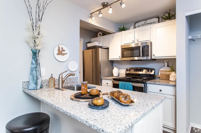 Modern kitchen with granite countertops, stainless steel appliances, and a breakfast bar.