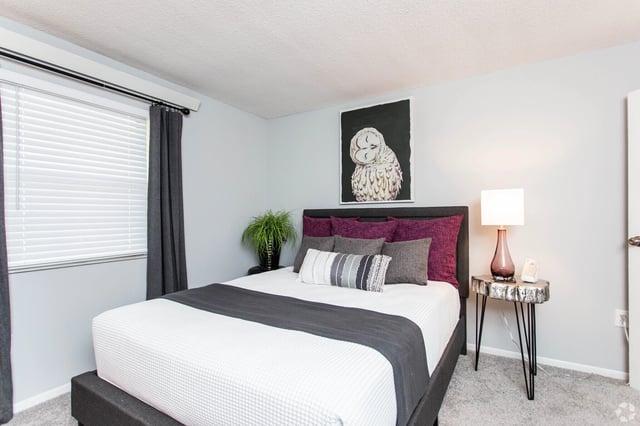 Cozy bedroom with a queen-size bed, plum and grey pillows, and an owl painting above the headboard.