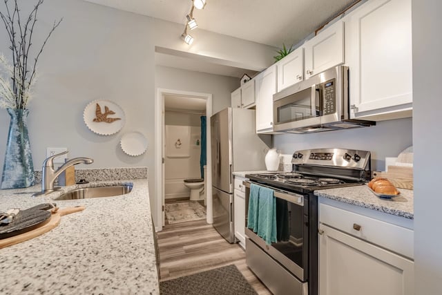 Modern kitchen with stainless steel appliances, granite countertops, and white cabinets.