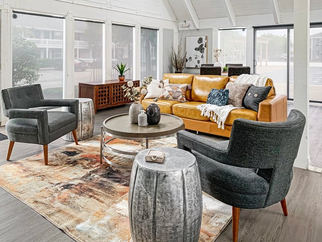 Stylish seating area with a tan leather sofa, dark gray armchairs, and a round coffee table.