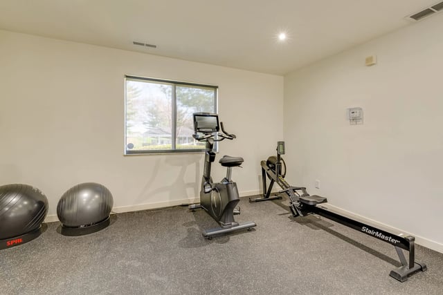 Stationary bike and rowing machine in a well-lit gym.