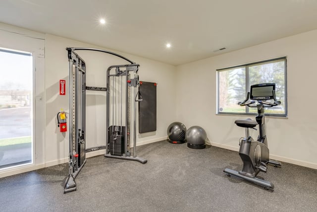 Gym with a cable crossover machine, exercise bike, and stability balls.