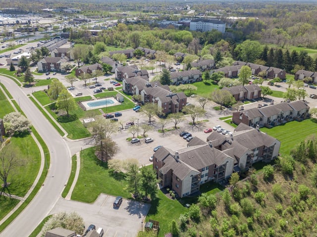 Aerial view of apartment buildings, parking lots, and an outdoor swimming pool.