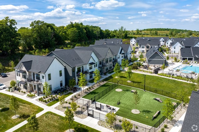 Aerial view of apartment buildings with a swimming pool and a dog park.