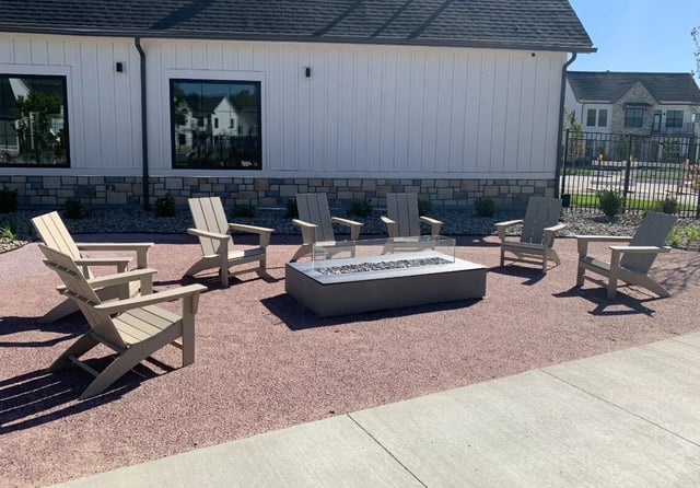 Patio seating area with Adirondack chairs around a gas fire pit.