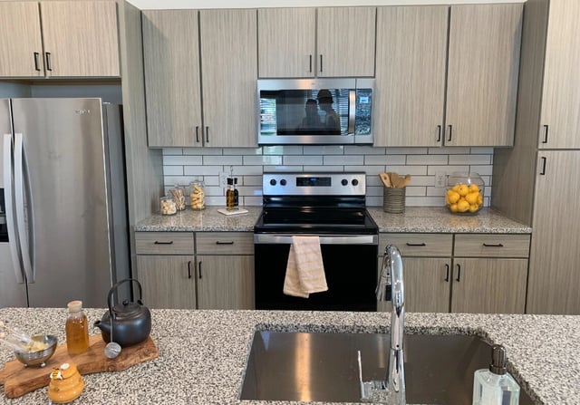 Modern kitchen with stainless steel appliances, granite countertops, and light wood cabinets.