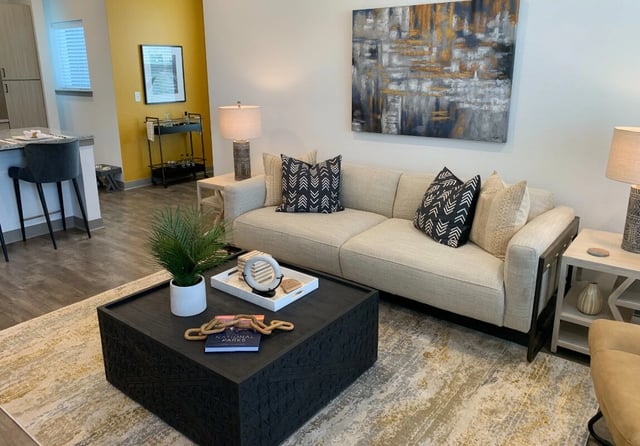 Modern living room with a light-colored sofa, black coffee table, and abstract art.