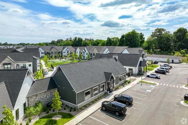 Exterior view of a modern apartment complex with multiple buildings and a parking lot.