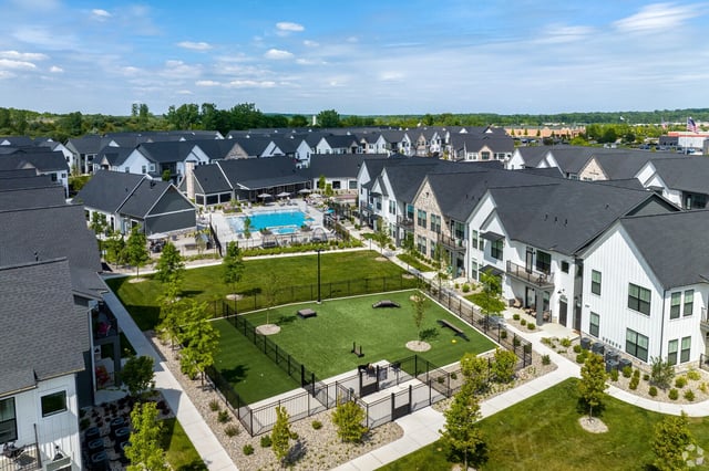 Aerial view of apartment buildings with a swimming pool and dog park.