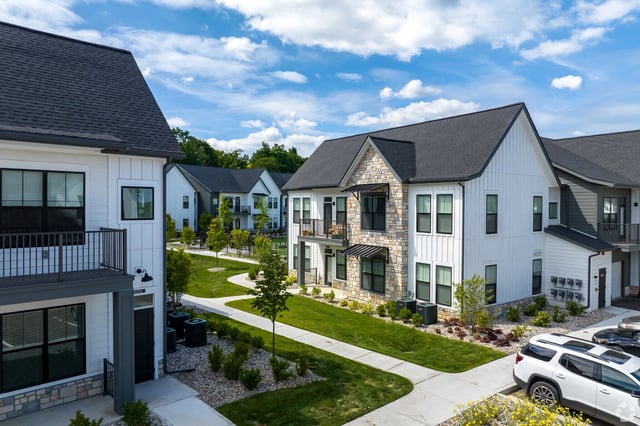 Modern apartment buildings with manicured lawns and pathways.