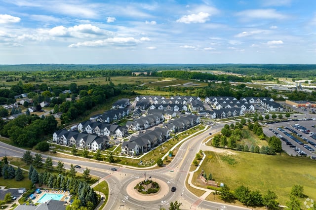 Aerial view of a modern apartment complex with multiple buildings and a swimming pool.