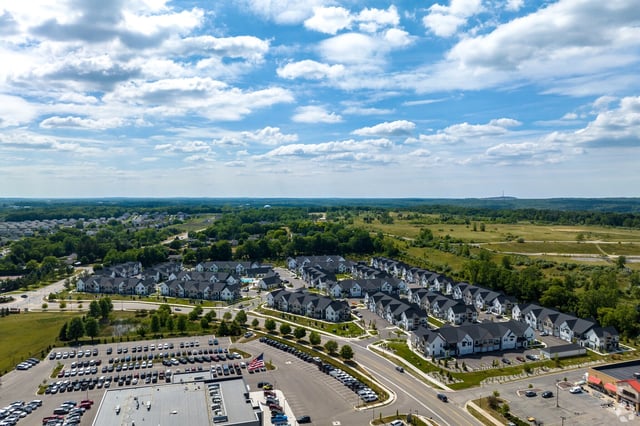 Aerial view of a townhouse community with a large parking lot in the foreground.