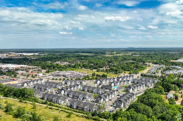 Aerial view of a suburban neighborhood with townhouses and a nearby commercial area.