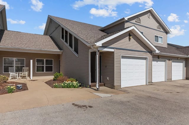 Exterior of apartment buildings with garages and a small seating area on the patio.