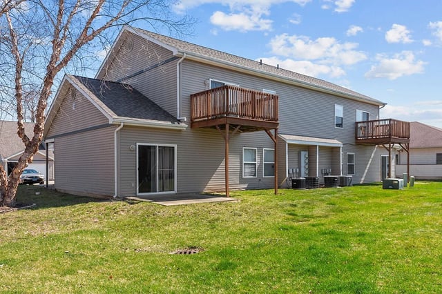 Rear exterior of a multifamily property with two levels, siding, and balconies.