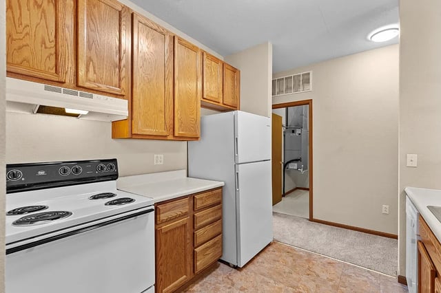 Kitchen with wood cabinets, white appliances, and a doorway to a utility area.
