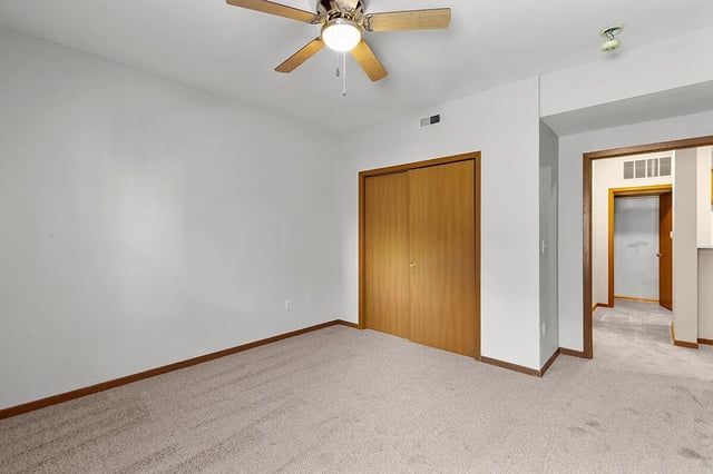 Bedroom with a ceiling fan and double closet doors.