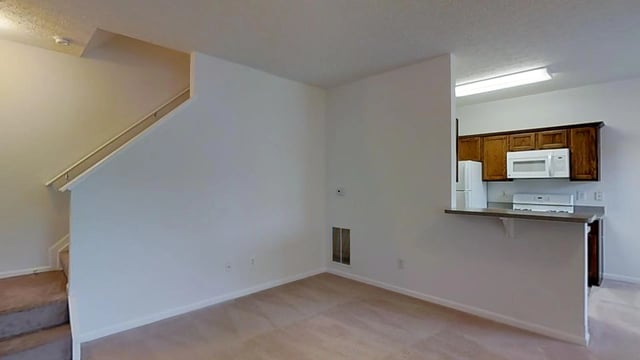 Interior view of a living room with stairs and a kitchen area.