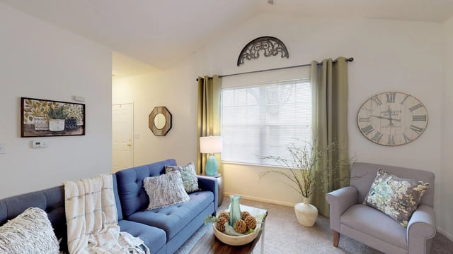 Comfortable living room with a blue sofa, armchair, coffee table, and decorative clock.