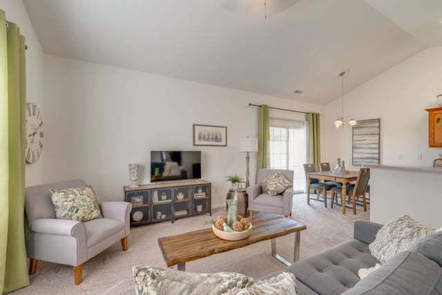 Living room and dining area with a sectional sofa, armchair, coffee table, TV, and dining table.
