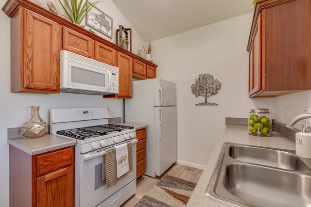 A clean kitchen with white appliances and wooden cabinets.