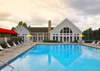 Outdoor swimming pool with lounge chairs and a clubhouse in the background.
