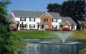 Apartment building exterior with a pond and fountain in the foreground.