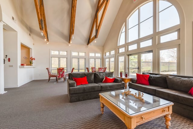 Clubhouse lounge area with plush sofas, coffee table, and large arched windows.