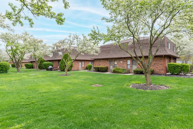 Brick apartment buildings with manicured lawns and blooming trees.
